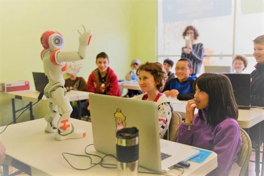 Teacher and kids gathered around a laptop for collaborative learning